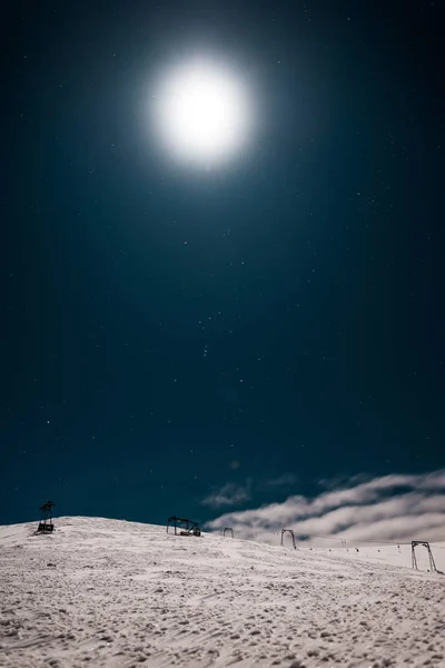 Vue panoramique de télécabine en montagne recouverte de neige contre ciel sombre avec soleil brillant — Photo de stock