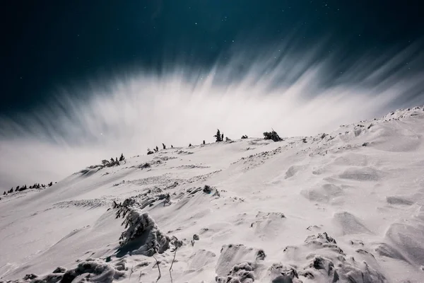 Vista panorâmica da montanha coberta de neve e pinheiros contra o céu escuro à noite com nuvem branca — Fotografia de Stock