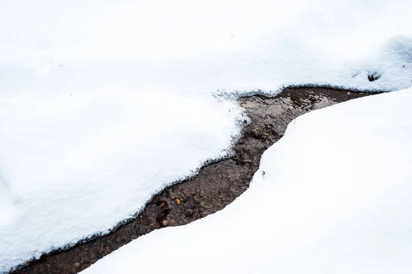 Torrente di montagna che scorre attraverso la neve bianca — Foto stock