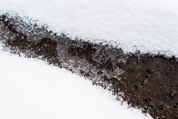 Гірський потік тече через білий сніг — стокове фото