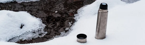 Vakuumkolben auf Schnee in der Nähe des fließenden Gebirgsbaches, Panoramaaufnahme — Stockfoto