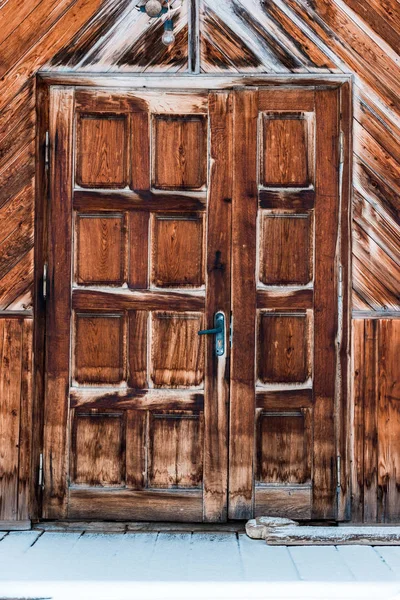 Wooden door in weathered rough house with pure snow — Stock Photo