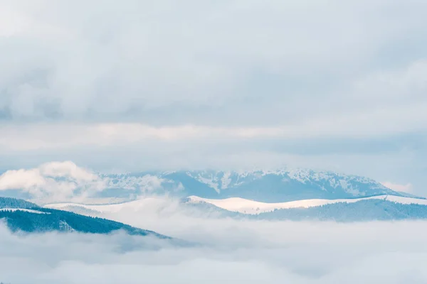 Мальовничий вид на засніжені гори в білих пухнастих хмарах — стокове фото