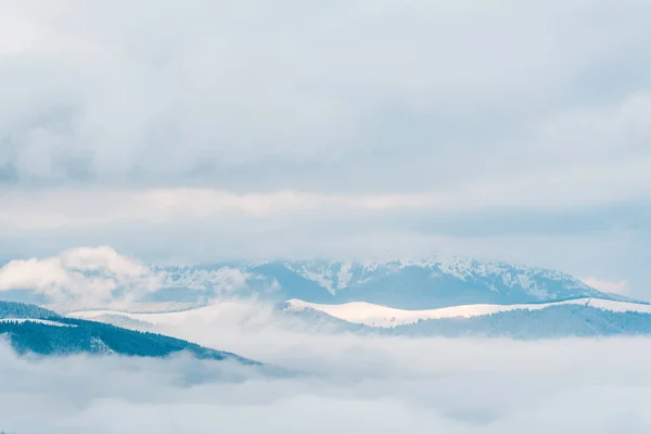 Scenic view of snowy mountains in white fluffy clouds — Stock Photo