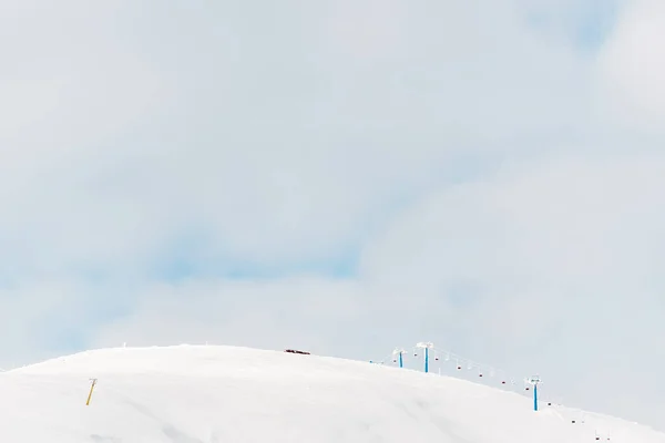 Мальовничий вид на засніжену гору з підйомом гондоли і білими пухнастими хмарами в небі — стокове фото