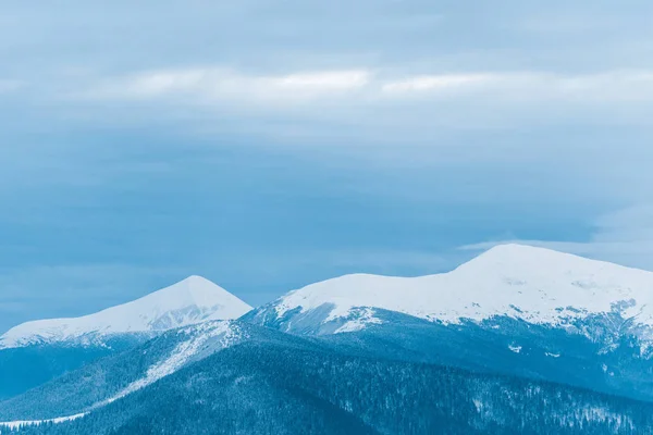 Vista panorámica de montañas nevadas y cielo nublado - foto de stock