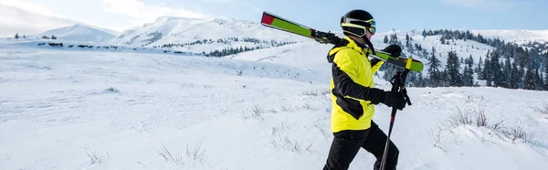 Panoramic shot of skier walking with sticks in mountains — Stock Photo