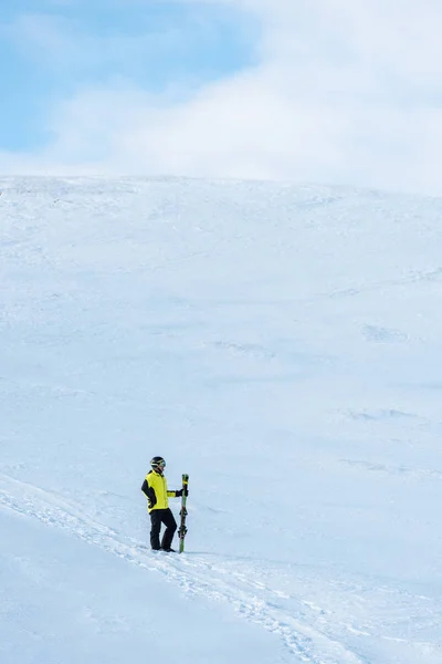 Sportler mit Helm steht mit Skistöcken auf weißem Schnee in den Bergen — Stockfoto