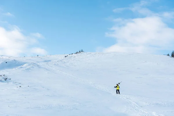 Deportista en casco caminando con bastones de esquí sobre nieve blanca en las montañas - foto de stock