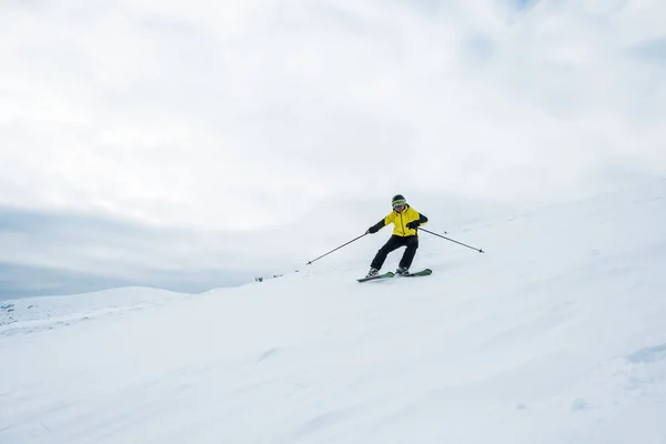 Sportsman holding ski sticks and skiing on white slope — Stock Photo