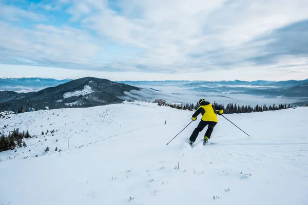 Обратно вид лыжника в шлеме катания на лыжах в зимнее время — стоковое фото