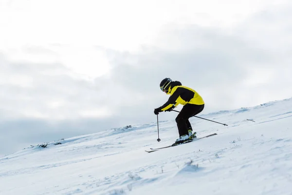 Desportista no capacete e óculos esquiando na encosta no inverno — Fotografia de Stock