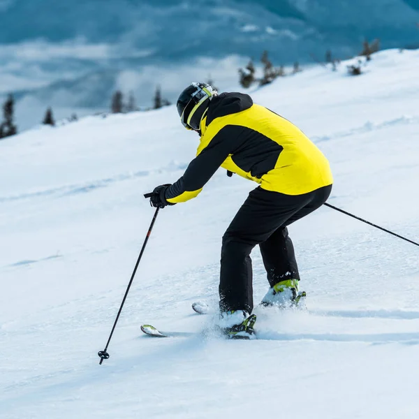 Skier in helmet skiing on slope near mountains — Stock Photo