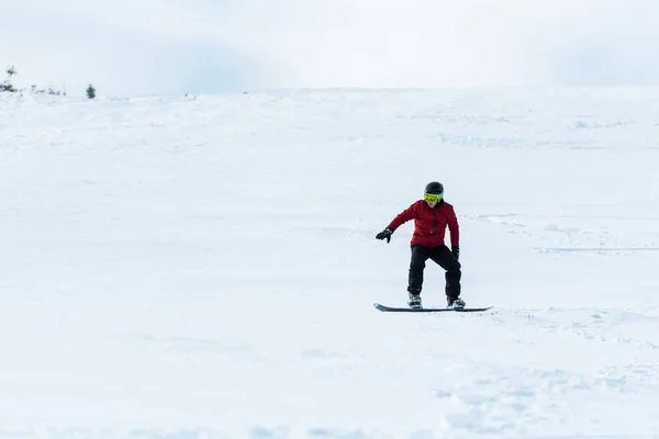 Snowboarder in helmet and gloves riding on slope with white snow outside — Stock Photo