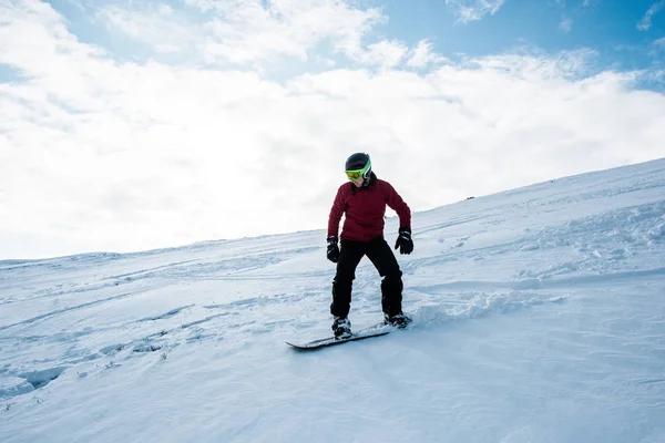 Snowboarder in helmet riding on slope against blue sky in winter — Stock Photo