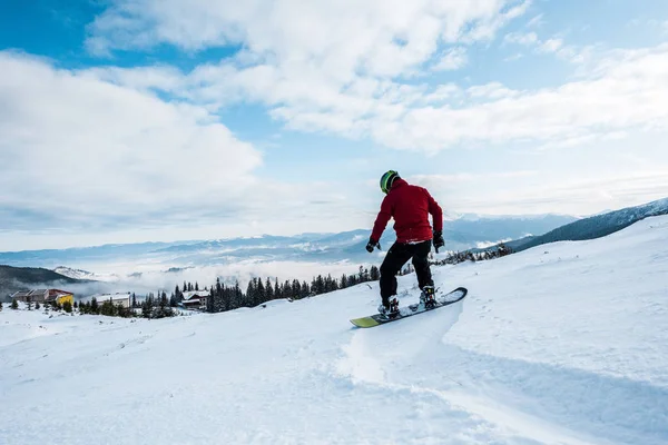 Snowboarder in maschera e casco a cavallo sul pendio in montagna — Foto stock
