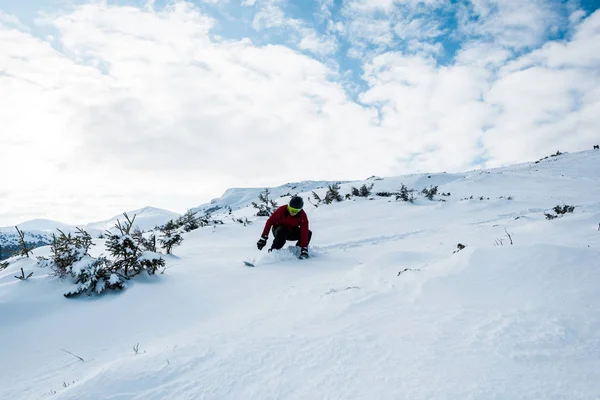 Сноубордист в окулярах і шоломі їде на схилі в горах на тлі блакитного неба — стокове фото