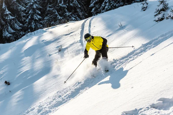 Sportif en casque tenant des bâtons de ski tout en skiant sur neige blanche — Photo de stock