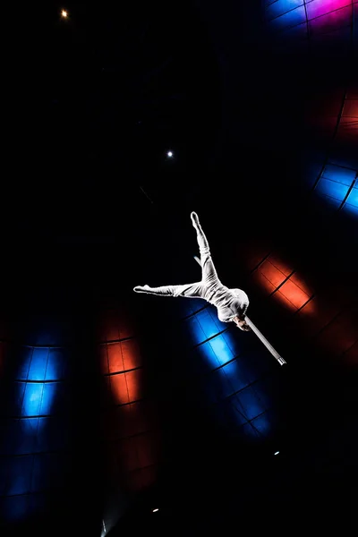 Vista en ángulo bajo del acrobat atlético balanceándose sobre poste metálico en arena de circo — Stock Photo