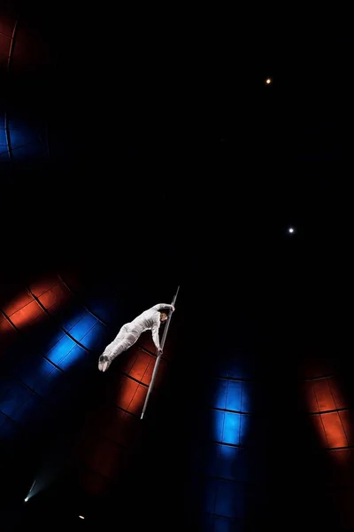 Blick auf einen athletischen Mann, der auf einer Metallstange in der Nähe der Beleuchtung in der Arena balanciert — Stockfoto