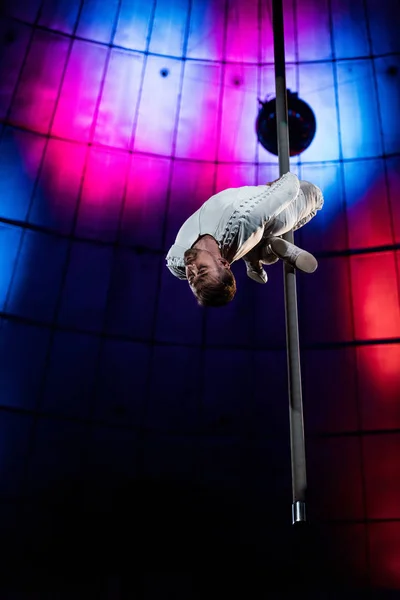 Strong acrobat with closed eyes performing on metallic pole — Stock Photo