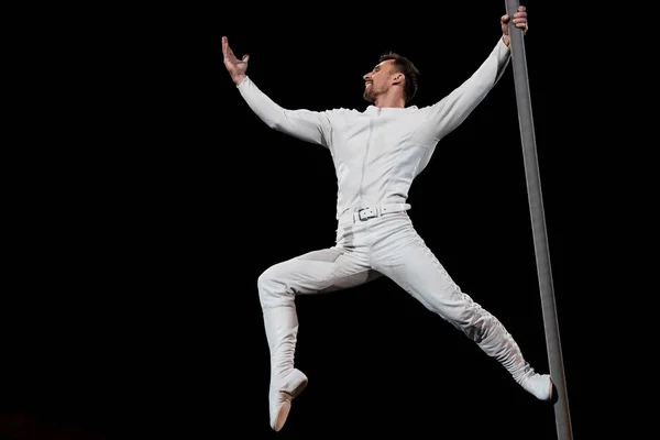 Strong acrobat posing while performing and holding metallic pole isolated on black — Stock Photo