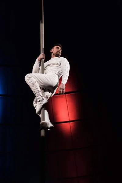 Low angle view of strong acrobat holding metallic pole while performing in circus — Stock Photo