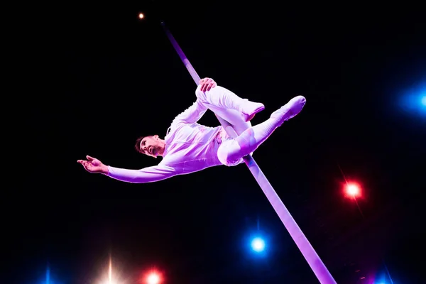 Back light near handsome acrobat holding metallic pole while performing in circus — Stock Photo