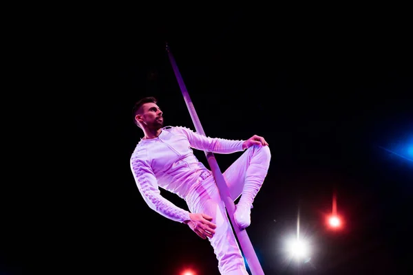 Low angle view of acrobat looking away while performing on black — Stock Photo