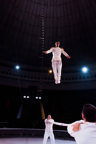 Acrobats celebración polo mientras guapo hombre saltar en circo - foto de stock