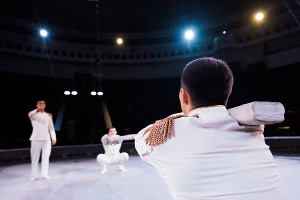 Selective focus of acrobat holding pole near men in circus — Stock Photo