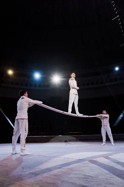 Gymnast standing on pole near acrobats in circus — Stock Photo