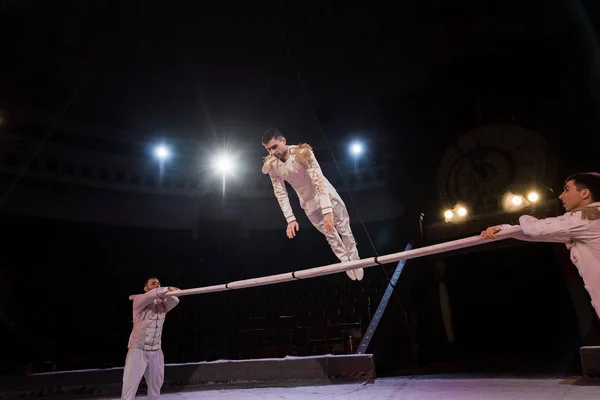 Handsome gymnast exercising on pole near acrobats in circus — Stock Photo