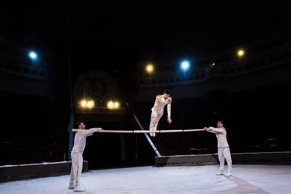 Гибкая гимнастка, тренирующаяся на шесте возле акробатов в цирке — стоковое фото