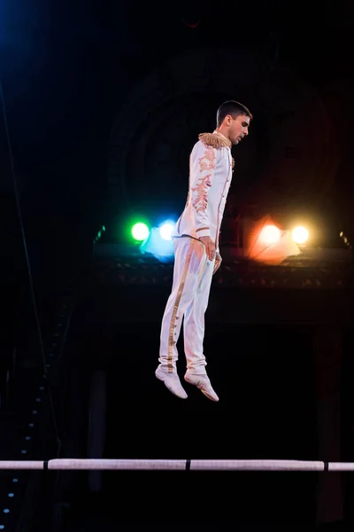 Handsome gymnast balancing near pole in arena of circus — Stock Photo