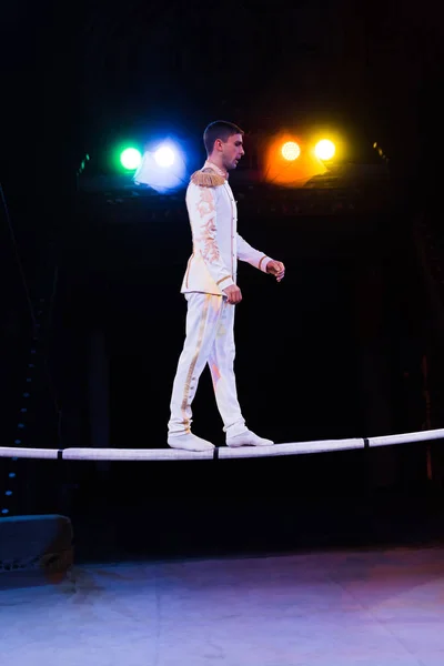 Vista lateral de gimnasta guapo en el equilibrio del traje mientras que camina en el poste en la arena del circo - foto de stock