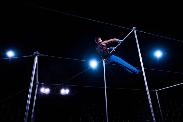 Visão de baixo ângulo de ginasta realizando em barras horizontais na arena de circo — Fotografia de Stock