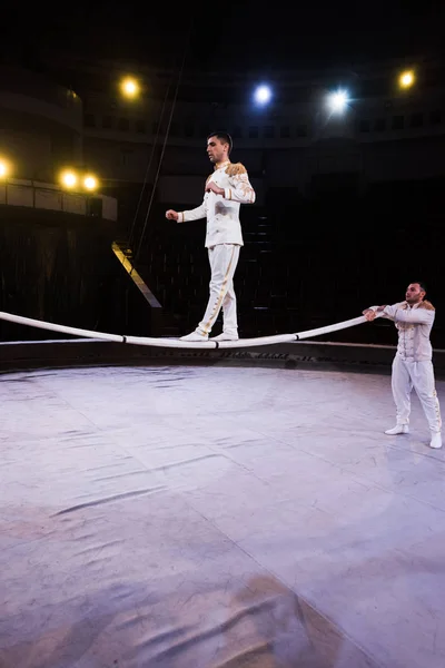 Air acrobat balancing on pole near gymnast in circus — Stock Photo