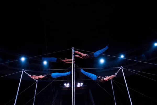 Four acrobats performing on horizontal bars in circus — Stock Photo