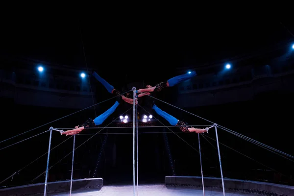 Four gymnasts exercising on horizontal bars in circus — Stock Photo