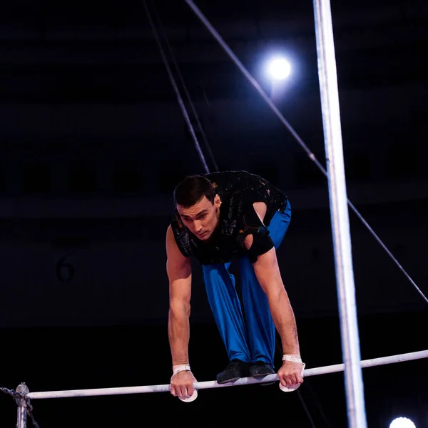 Gymnaste athlétique performant sur des barres horizontales dans l'arène du cirque — Photo de stock