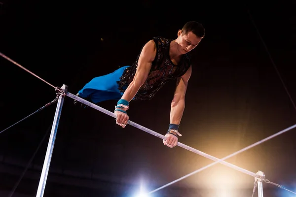 Gymnaste athlétique performant sur des barres horizontales dans l'arène du cirque — Photo de stock