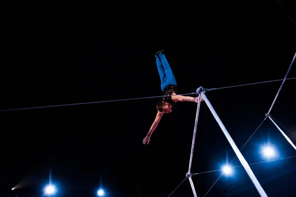 Low angle view of athletic man performing on horizontal bars in arena of circus — Stock Photo