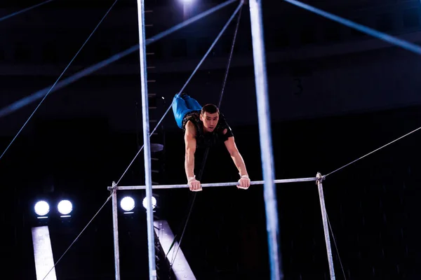 Focalizzazione selettiva di ginnasta atletica che esegue su barre orizzontali in arena di circo — Foto stock