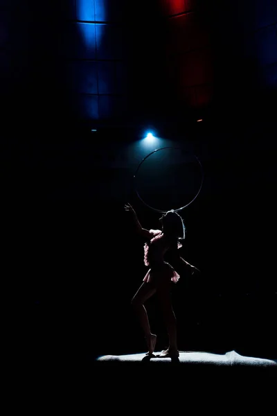 Silhouette of aerial acrobat standing on rope with hula hoop — Stock Photo