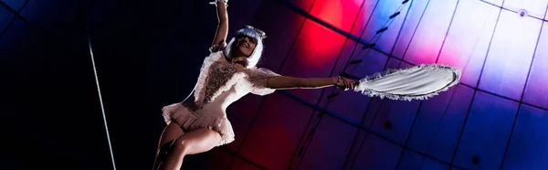 Panoramic shot of attractive aerial acrobat holding racket while standing on rope — Stock Photo