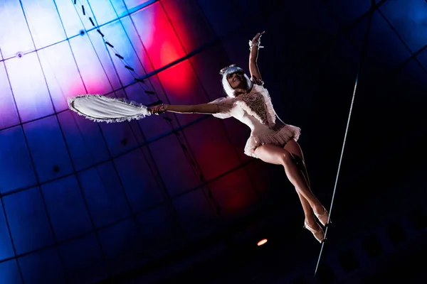 Attractive aerial acrobat holding racket while standing on rope — Stock Photo
