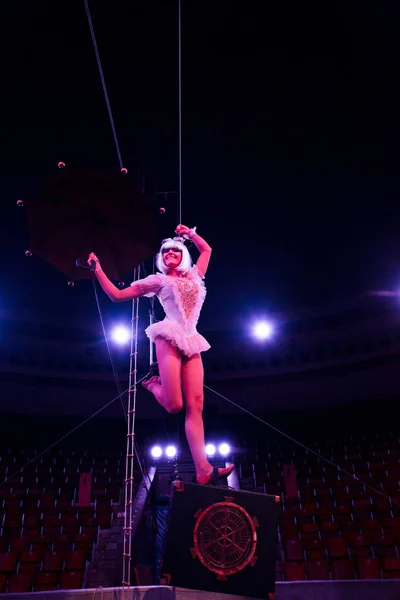 Artistic aerial acrobat holding umbrella while performing in circus — Stock Photo