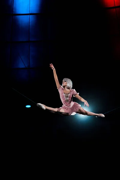 Acrobat aéreo artístico haciendo splits mientras se realiza en circo - foto de stock
