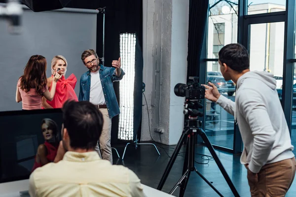 Selective focus of makeup artist near model and art director — Stock Photo